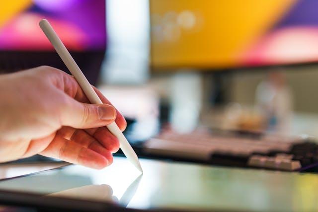 A person drawing in front of colorful computer monitors